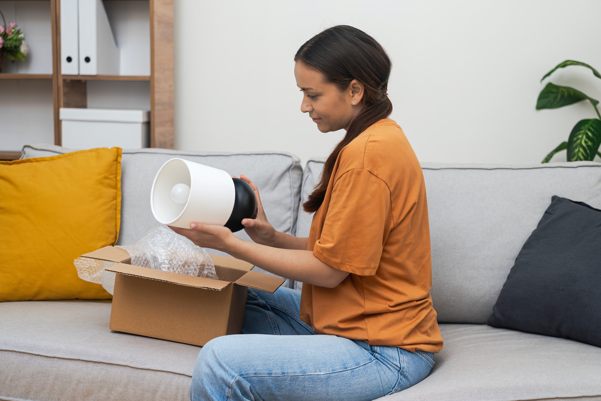 Concentrated lady carefully examines purchased lamp from online furniture store with home delivery